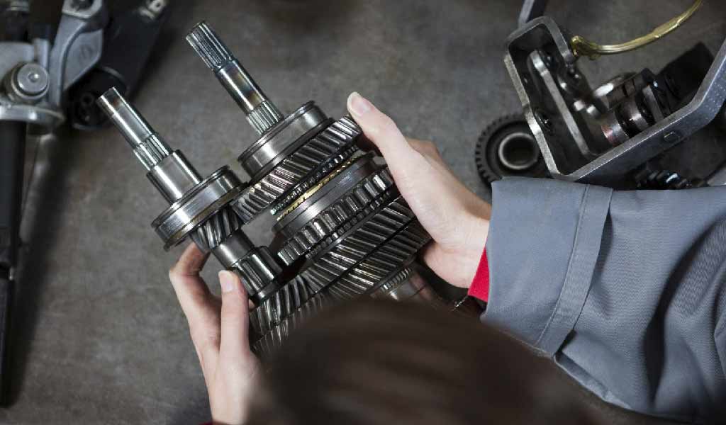 An operator holds a part in her hands in a manufacturing workshop.